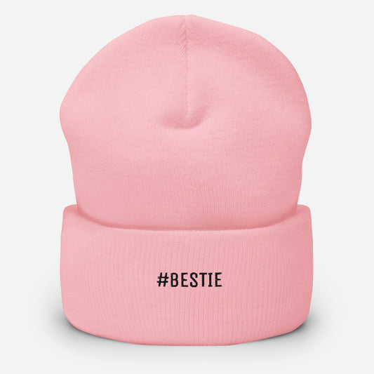 Pink beanie with '#BESTIE' text on a light gray background
