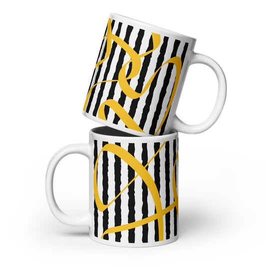 Two mugs with black and white striped pattern and yellow abstract designs stacked on a white background